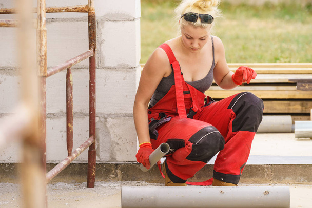 Vrouw installeren leidingen op bouwplaats - Foto, afbeelding