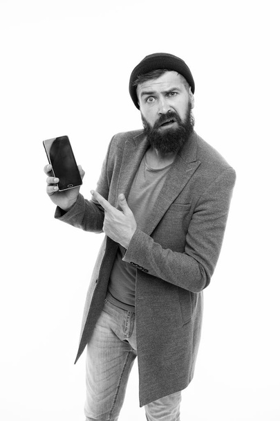 User outraged. Man brutal bully appearance hold smartphone isolated white. Bearded brutal guy pointing at smartphone. Smartphone user outraged mobile application. Client unsatisfied with smartphone - Foto, afbeelding