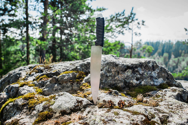cuchillo de caza atascado en la roca en el bosque
 - Foto, Imagen
