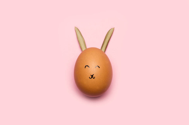 An egg with face and rabbit ears on a pink background - Photo, image