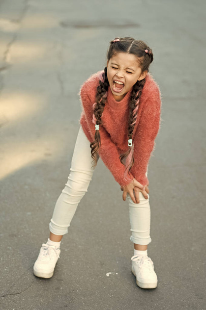 Small child has pain in knee. shouting little girl in autumn sweater. Autumn snuggles. Autumn fashion for pretty girl. healthy childhood. leg injury of little girl. Pure feelings. Melancholic mood - Фото, изображение