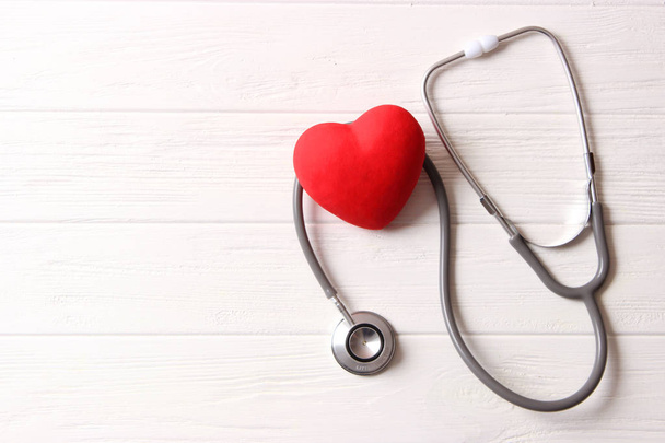 Stetoskop i serce na drewnianym tle koloru. Zdrowie, medycyna - Zdjęcie, obraz