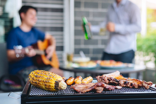 Group of friends Two young man enjoying grilled meat and play gu - Photo, Image