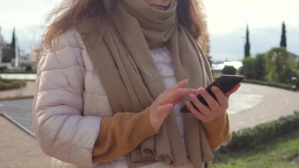 Adult woman is swiping over smartphone screen outdoors on city street, close-up - Metraje, vídeo