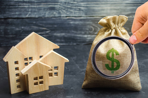 A bag with money and wooden houses. Selling a house. Apartment purchase. Real estate market. Rental housing for rent. Home prices. Mortgage interest. Purchase demand. Property valuation. Insurance - Photo, image
