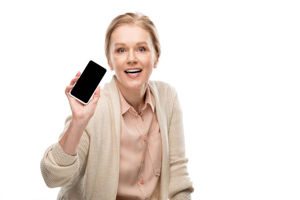 vzrušená žena středního věku zobrazující smartphone s prázdnou obrazovkou izolované na bílém - Fotografie, Obrázek