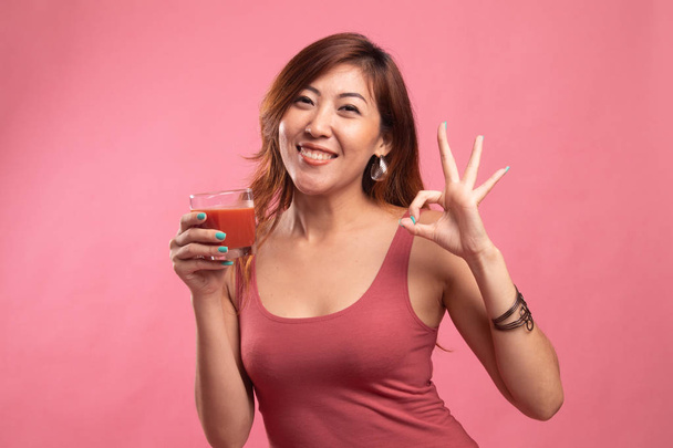 Young Asian woman show OK with tomato juice. - Zdjęcie, obraz