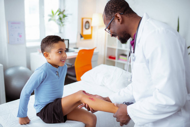 Cute little boy visiting pediatrician after scratching his leg - Φωτογραφία, εικόνα