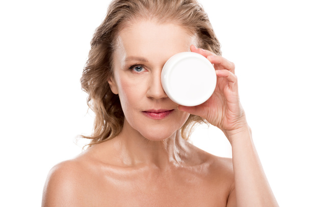 atrakcyjna dojrzała kobieta trzyma pojemnik z kosmetykiem krem na białym tle - Zdjęcie, obraz