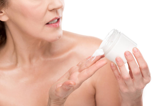 oříznutý pohled dospělé ženy držící nádobu s kosmetickou smetanovou izolovanou na bílém - Fotografie, Obrázek