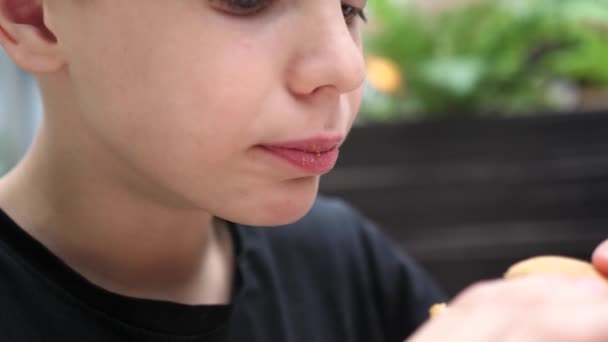 Uma criança come um pão com uma costeleta e queijo em um restaurante de fast food
 - Filmagem, Vídeo