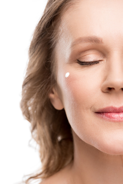 Обрізаний вид зрілої жінки з косметичним кремом на обличчі Ізольовані на білому
 - Фото, зображення