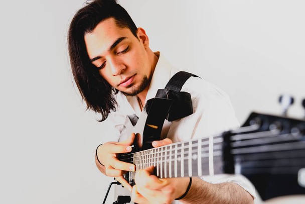 Gitarist poseren met zijn elektrische gitaar, witte achtergrond. - Foto, afbeelding