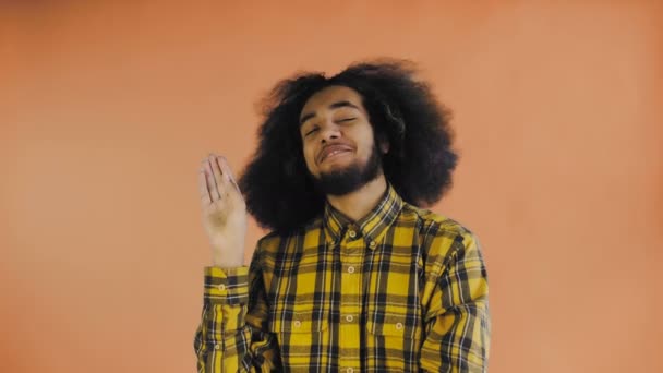 Joven afroamericano mostrando silencio o gesto bla bla sobre fondo naranja. Concepto de emociones
 - Metraje, vídeo