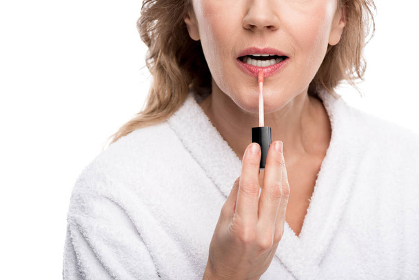 Vista recortada de la mujer madura aplicando brillo labial aislado en blanco
  - Foto, Imagen