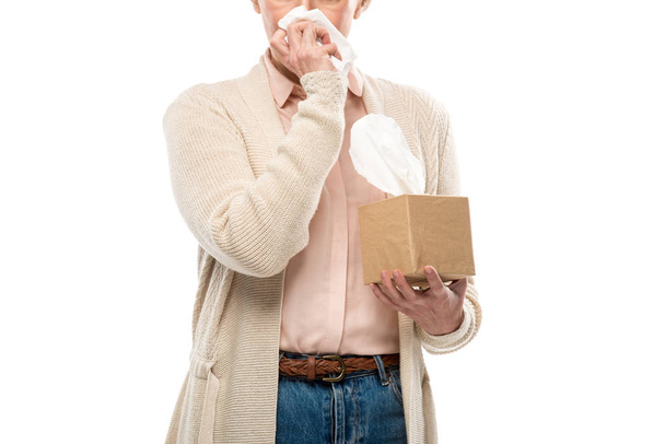 bijgesneden beeld van middelbare leeftijd vrouw huilen en vegen gezicht met weefsel geïsoleerd op wit - Foto, afbeelding