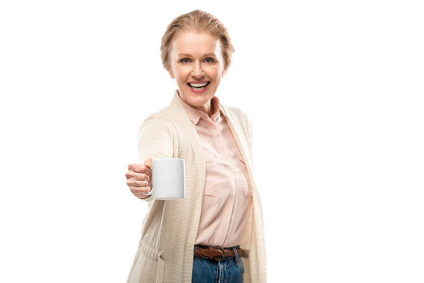 χαρούμενη μεσήλικη γυναίκα που δείχνει κούπα καφέ με χώρο αντιγραφής απομονωμένη σε λευκό - Φωτογραφία, εικόνα
