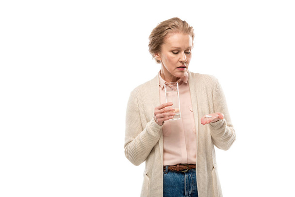 Женщина средних лет со стаканом воды и таблетками, изолированные на белом с копировальным пространством
 - Фото, изображение