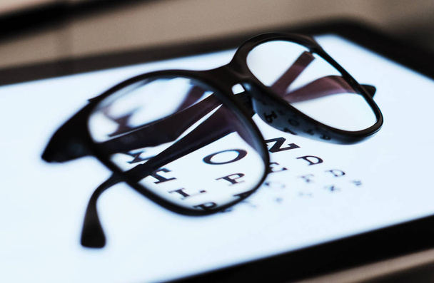 eye chart sulla compressa e sul vetro con E Standard Logarithm Eyesight Tablet sulla parte superiore dello schermo luminoso
 - Foto, immagini