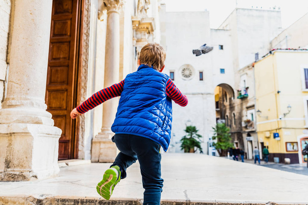 Child from behind running to enter a church. - Photo, Image