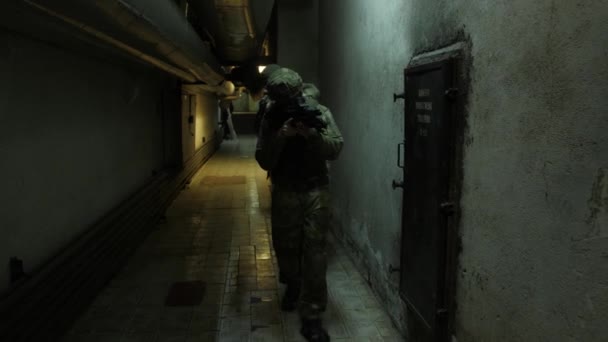 Soldats entièrement équipés portant l'uniforme de camouflage attaquant l'ennemi, fusils prêts à tirer. Airsoft joueur en camouflage complet passe à l'intérieur du bâtiment
. - Séquence, vidéo