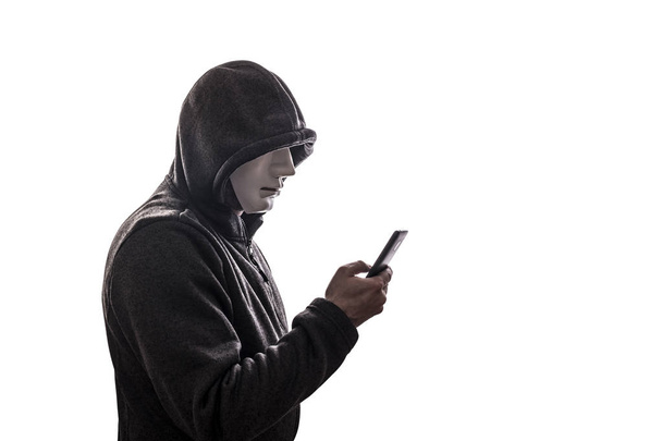 Hooded hacker with mask holding smartphone isolated on white background  - Photo, Image