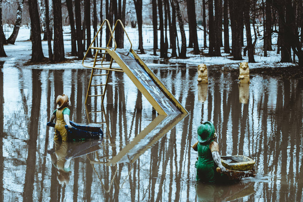 Figurine in forma di gnomi sta con la schiena con le carriole in acqua in primavera nella realtà russa. La neve si sta sciogliendo, creando una pozzanghera enorme. Atmosfera come in fiaba
. - Foto, immagini