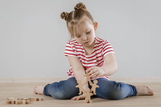 The development of soft skills in the child. Girl playing with wooden figures. - Photo, Image