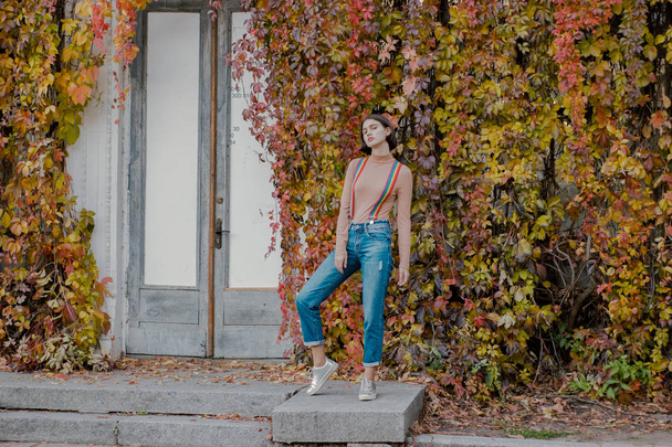 Young girl in multi-colored suspenders next to door - Fotoğraf, Görsel