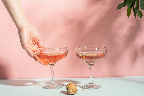 Champán o vino en varias copas elegantes y fondo rosa mano femenina luz brillante. Copiar espacio. Enfoque selectivo
. - Foto, Imagen
