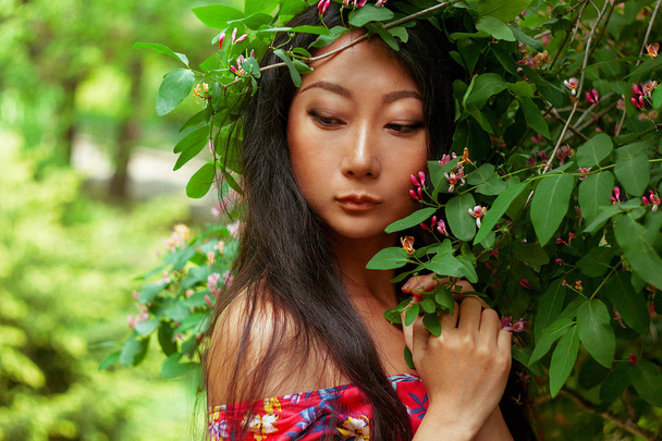 Summer portrait of beautiful Asian woman with long hair on green background. - Photo, Image