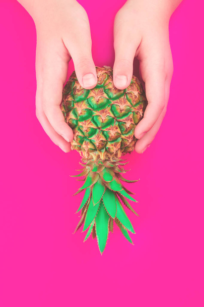 Hands with pineapple on summer neon pink background - Фото, изображение