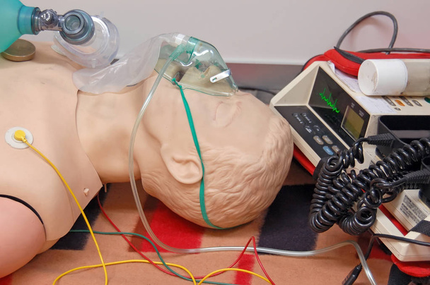 Manekin do treningu pierwszej pomocy z maską oddechową i czujnikami połączonymi z jednostką elektrokardiografią  - Zdjęcie, obraz