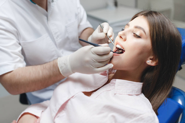 Dental clinic. Reception, examination of the patient. Teeth care. Young woman undergoes a dental examination by a dentist.Happy patient and dentist concept.Female dentist in dental office talking with girl patient.Beautiful teeth - Foto, imagen
