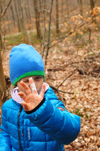 menino encontra um cache durante geocaching e mostra seu dedo ferido com gesso na câmera
 - Foto, Imagem
