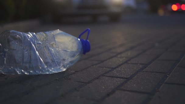Plastová láhev ležící na zemi v noci před autem-vyhozena nerecyklovaná-odpadky a znečištění města a přírody-zkažená smetí - Záběry, video