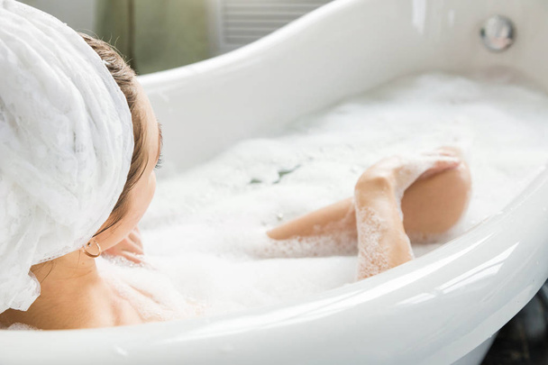 Una giovane ragazza attraente si rilassa in bagno e riposa sullo sfondo di un bellissimo interno leggero. Trattamenti Spa per la bellezza e la salute con la cura della pelle
 - Foto, immagini