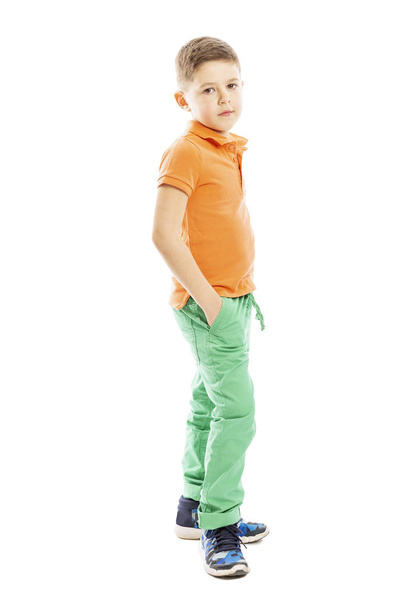 オレンジ色のTシャツを着たかわいい男の子が立っています。垂直。白い背景に隔離.  - 写真・画像