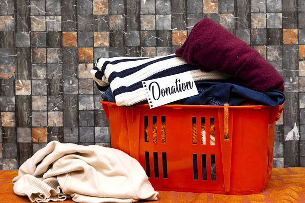 roupas em cesta de laranja ou caixa com cartão de doação
  - Foto, Imagem