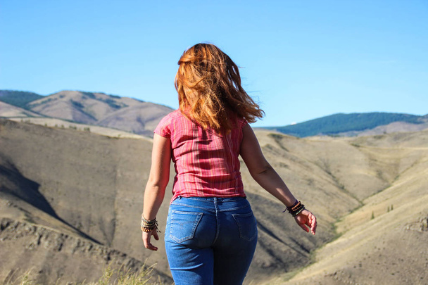 Gordinha menina turista com cabelo vermelho em jeans nas montanhas
 - Foto, Imagem