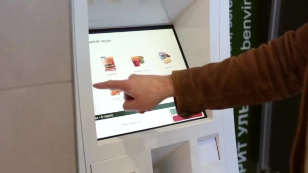 Rusya, Moskova, 17.04.2019: Fast food restoranında self servis makine ile yemek seçen adam. Self servis dokunmatik terminalkullanan adam - Video, Çekim