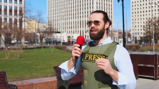 Επιτυχημένος δημοσιογράφος με μικρόφωνο στο χέρι μιλάει ζωντανά στο δρόμο - Πλάνα, βίντεο