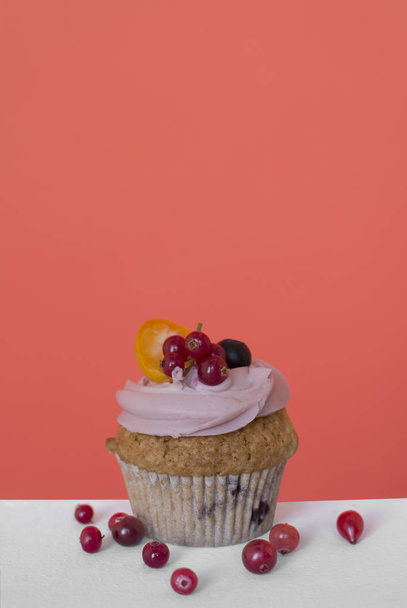 cupcake doce com frutas e bagas em um fundo de coral
 - Foto, Imagem