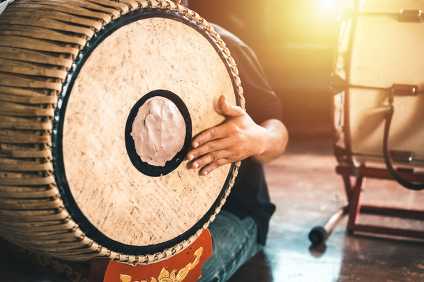 Asian male hit a two-faced drum to make music. - Photo, Image
