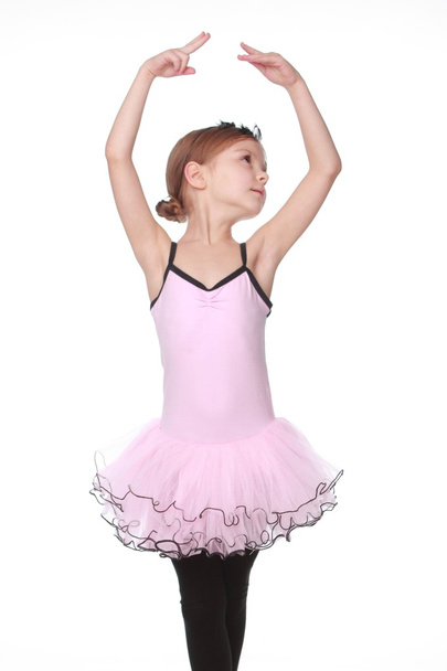 Portrait of a smiling little dancer in pink tutu standing in a ballet pose - 写真・画像