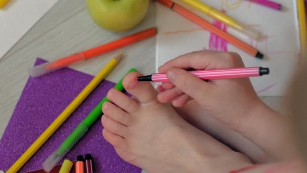 little girl draws on her feet with felt-tip pens, childrens creativity, development - Footage, Video