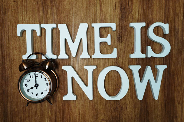 Time Is Now alphabet letter with alarm clock on wooden background - Fotó, kép