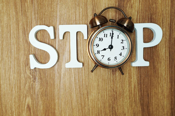 Stop Word alphabet letters and alarm clock Top Viw on wooden background - Fotó, kép