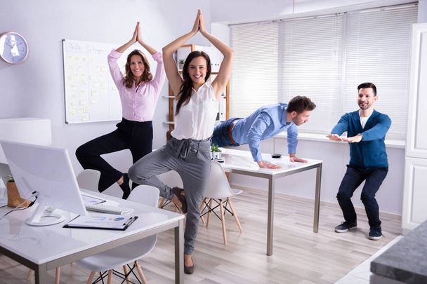 Smiling Young Businesspeople Doing Yoga In Office - Φωτογραφία, εικόνα