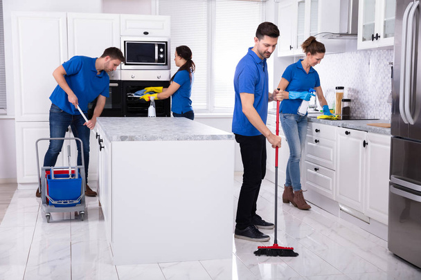 Group Of Young Janitors In Uniform Cleaning Kitchen At Home - Foto, Imagem